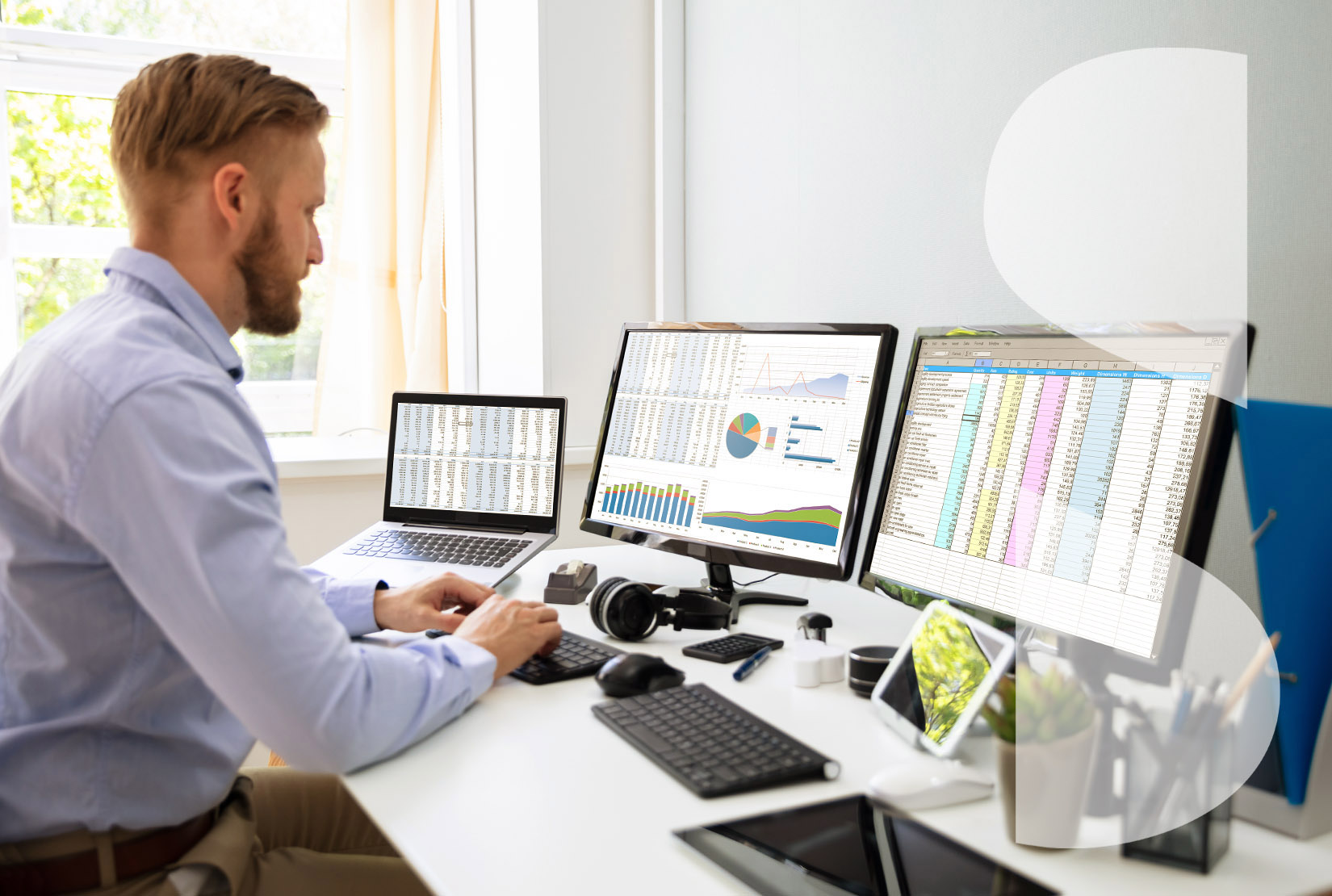 Businessman working with spreadsheets on multiple desktop and laptop computer screens