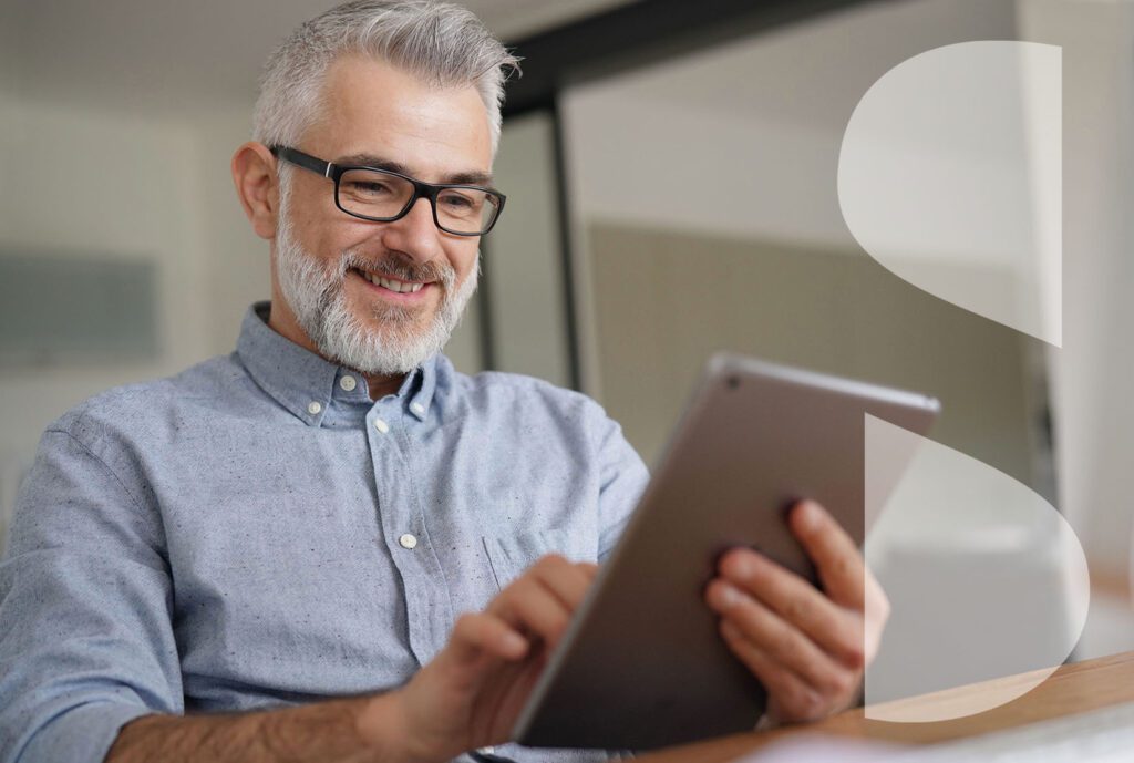 Mature man with graying hair smiles while looking at a tablet. Semi-transparent ImageSource icon is overlaid.