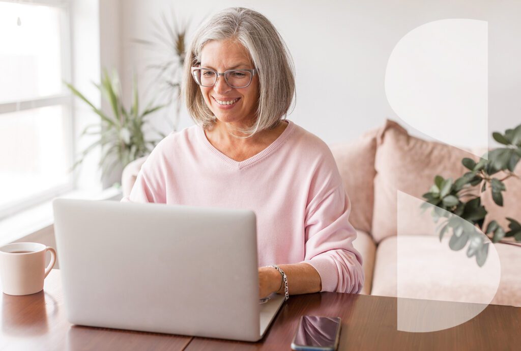 An attractive senior woman uses a home laptop.